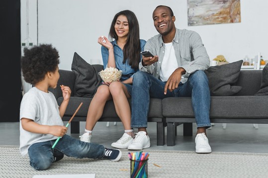 Family sitting on couch spending time together watching TV