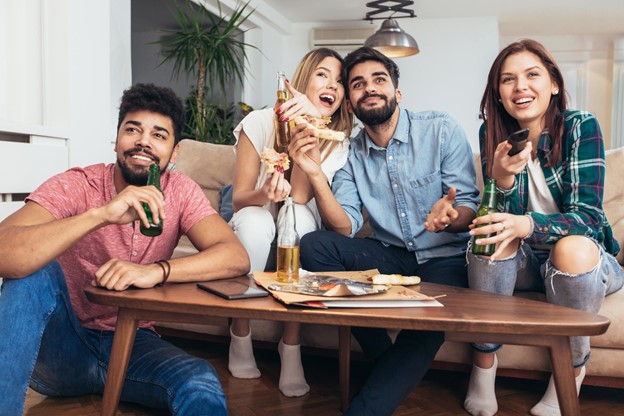Four Friends Watching TV Enjoying Pizza and Beverages