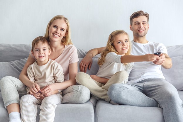 Family of four sitting on the couch watching television