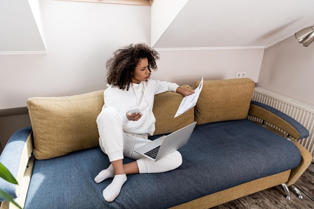 Young woman working remotely and sitting on the couch with laptop